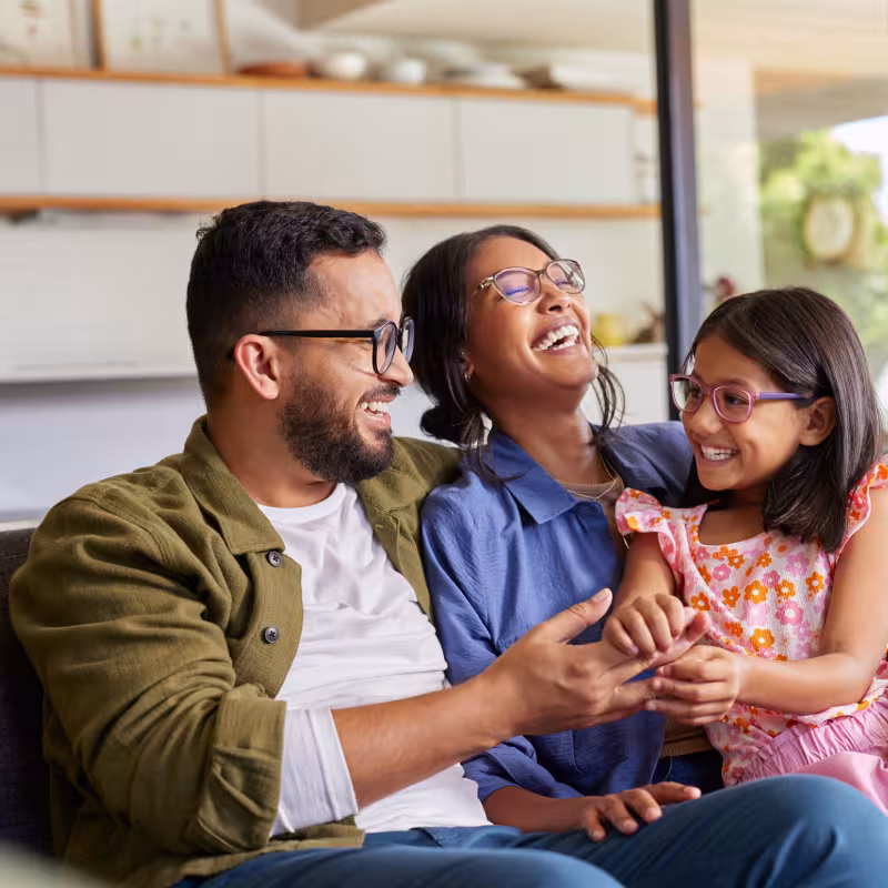 Cheerful family embracing and playing with daughter in arms.